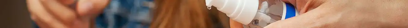 Person disinfecting hands in a modern public environment with hygiene and surface cleaning products